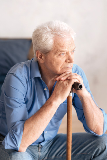 Old age. Nice grey haired pensive man sitting and leaning on the walking stick while being involved in his thoughts